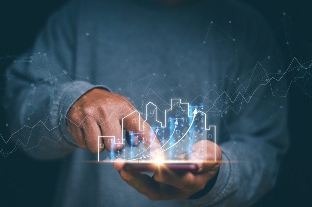 Geschäftsmann mit Handy in der Hand und einem Diagramm zum Wachstum des Vermögensgeschäfts, Konzept des geschäftlichen Wohlstands und der Vermögensverwaltung, Marketinganalyse für Immobilieninvestitionen, Planung zur Gewinnsteigerung.